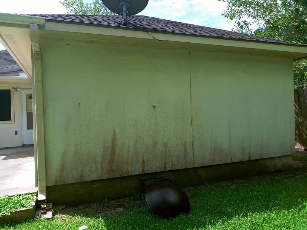 Stucco wall severely stained before soft washing by LKJ Preferred Services, Houston TX