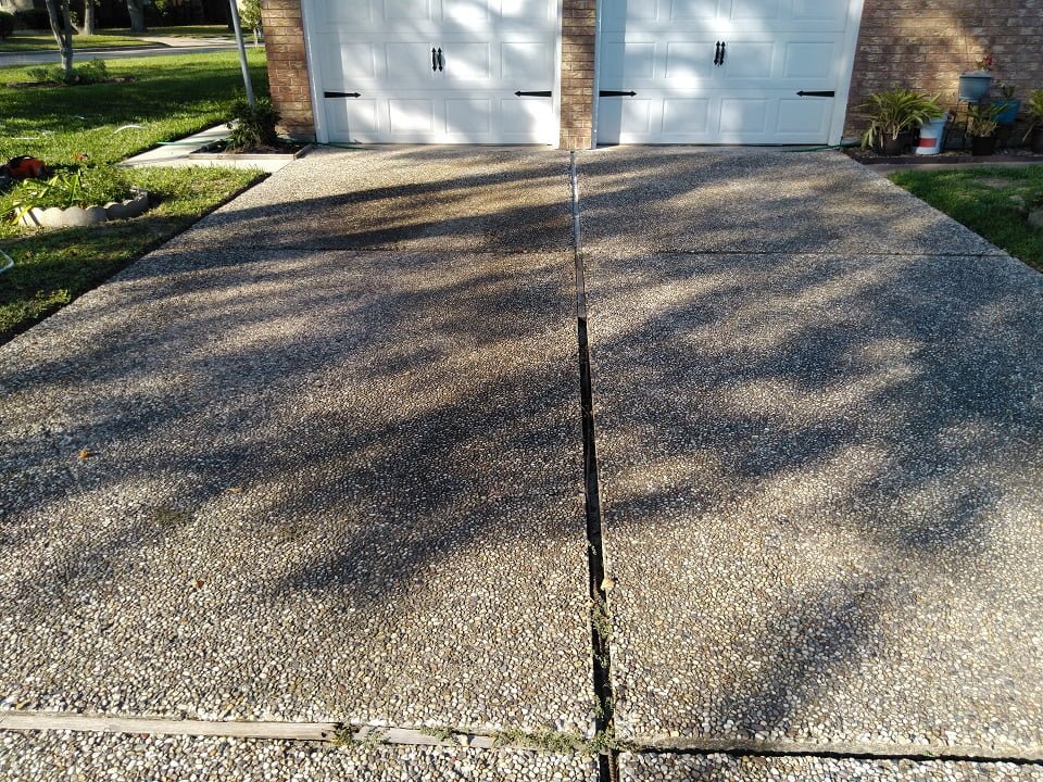 Pea rock driveway with oil and rust stains before cleaning by LKJ Preferred Services, Houston TX