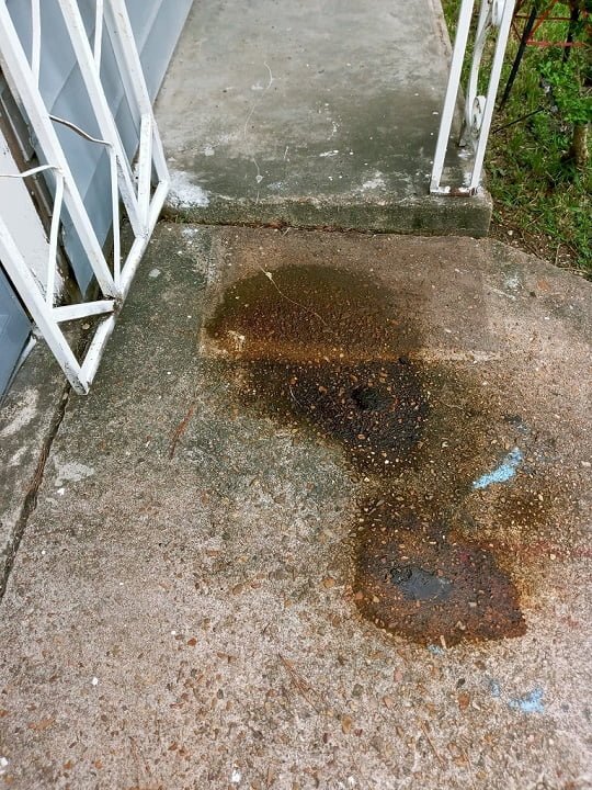 Driveway with rust and tar stains before cleaning by LKJ Preferred Services, Houston TX
